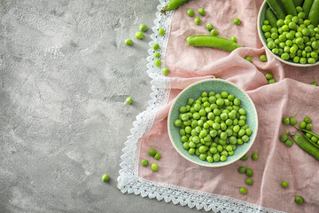 Bowls with green peas on light background