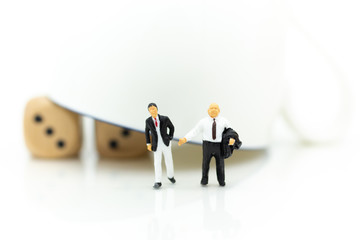 Miniature people: Businessman with a glass with dice inside, risky investment. Image use for business concept.