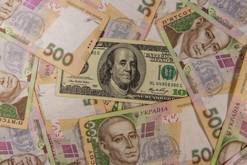 Fototapeta na wymiar One hundred dollar bill on the background of ukrainian five hundred hryvnia banknotes