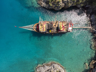 Aerial over a sailing ship in turquoise water on a bright day in Oludeniz, Turkey