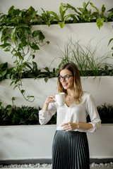 Young woman with mug standing in the office