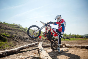Hard enduro motorcycle rider crossing logs on an obstacle course. Extreme outdoor sports.