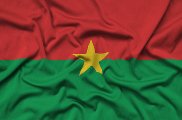 Burkina Faso flag  is depicted on a sports cloth fabric with many folds. Sport team banner
