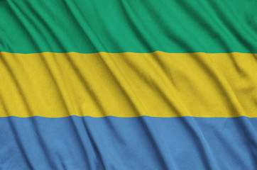 Gabon flag  is depicted on a sports cloth fabric with many folds. Sport team banner