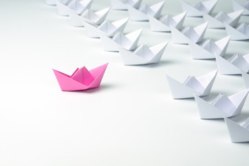 Woman leadership concept with pink paper ship.
