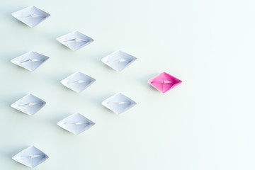 Woman leadership concept with pink paper ship leading among white on white background.