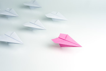 Woman leadership concept with pink paper plane leading among white.