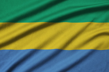 Gabon flag  is depicted on a sports cloth fabric with many folds. Sport team banner