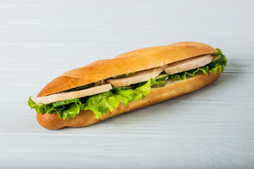 Fresh submarine sandwich with ham, cheese, tomatoes, cucumbers, lettuce and onions isolated on white background