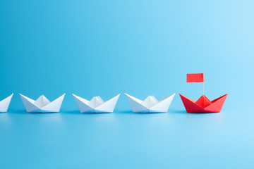Leadership concept. Red leader paper ship leading among white on blue background.