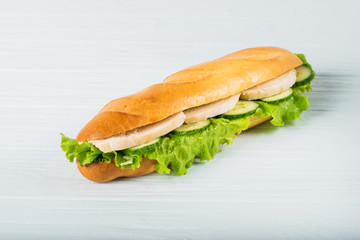 Fresh submarine sandwich with ham, cheese, tomatoes, cucumbers, lettuce and onions isolated on white background