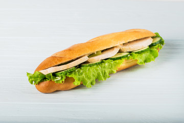 Fresh submarine sandwich with ham, cheese, tomatoes, cucumbers, lettuce and onions isolated on white background
