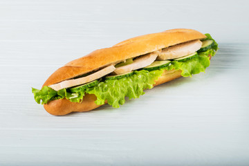 Fresh submarine sandwich with ham, cheese, tomatoes, cucumbers, lettuce and onions isolated on white background