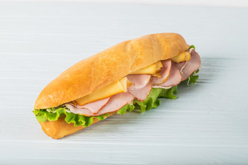 Fresh submarine sandwich with ham, cheese, tomatoes, cucumbers, lettuce and onions isolated on...