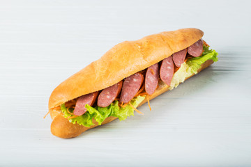 Fresh submarine sandwich with ham, cheese, tomatoes, cucumbers, lettuce and onions isolated on white background