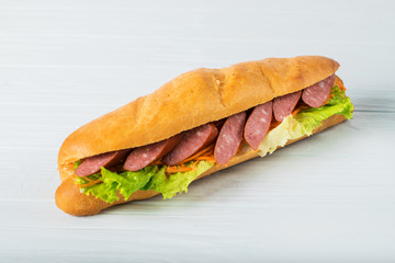 Fresh submarine sandwich with ham, cheese, tomatoes, cucumbers, lettuce and onions isolated on white background