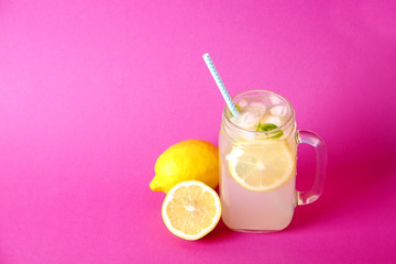 Ice cold lavander lemonade, lemon, straw, mint. Classic virgin mojito cocktail, non alcoholic drink with ice in vintage mason jar glass, bright pink isolated background. Copy space, top view close up.