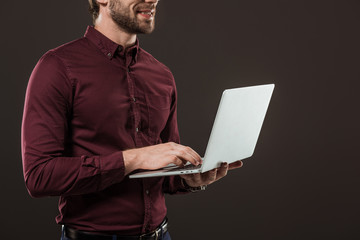 cropped shot of smiling man using laptop isolated on black