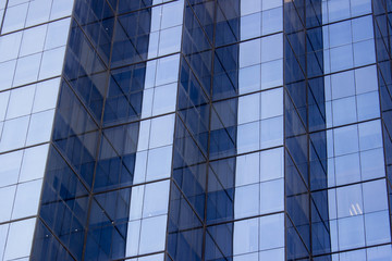 Obraz premium A glass window wall of an office building with several corners. The light and the position of the window walls generate a contrast effect.