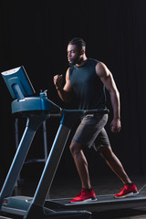 Fototapeta na wymiar handsome young african american sportsman running on treadmill
