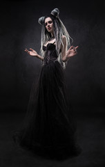 Woman with dreads and black gothic dress posing on dark background