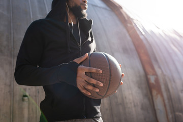 cropped shot of african american man holding basketball ball on street