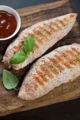 Close-up of bbq turkey breast fillet on a rustic wooden serving board, selective focus, vertical shot