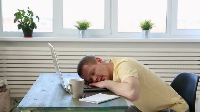 freelance programmer falls asleep from fatigue at his desk with a laptop