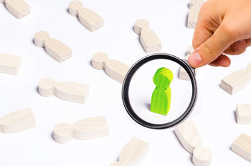 A person is in the spotlight. A green wooden figure of a man. Concept business idea. Best in the business. People lie around. Victory, progress, innovation.