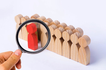 The chosen person among others. A human figure of red color stands out from the crowd. Wooden...