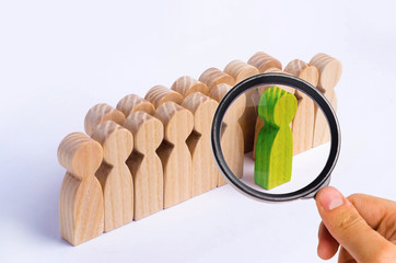 The chosen person among others. A human figure of green color stands out from the crowd. Wooden...