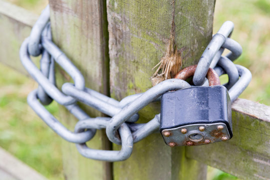 Padlock locked with a metal chain on a gate