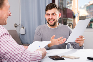 Happy man discussing papers with male colleague
