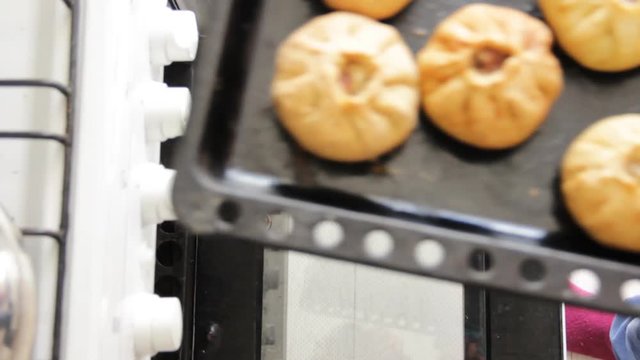 Women opens oven and take off prepared hot vak belyash - bashkir national homemade meat pies. Top view.