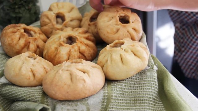 Prepared vak belyash - bashkir national homemade meat pies at home kitchen. Housewife put fresh hot pastry on the cloth