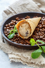 Coffee ice cream with chocolate drops in a waffle cone.