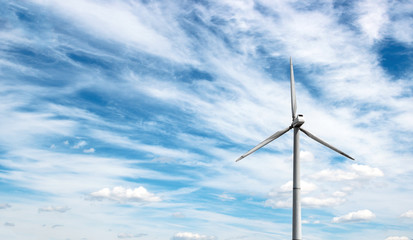 wind generator of electricity from three blades against the background of clouds and blue sky