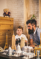 Planning their trip. Looking for adventure. Man and little child with binocular and miniature architecture. Boy son and father with world landmark buildings in miniature. Discovering new places
