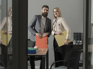 Working and communicating together. Happy colleagues in modern office. Business couple smile meeting in office. Bearded man and sensual woman smiling with binders, paperwork. Work process concept
