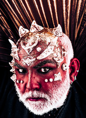 Devil with cunning look tempting people. Demon head with thorns on face appearing from darkness, horror and nightmare concept. Monster with red skin on black background