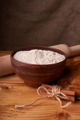 A bowl with flour and apricot cake on a wooden background