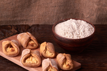 flour in clay bowl products for making cheesecakes on a wooden chopping board. Homemade Cottage cheese cookies on black background. still life composition