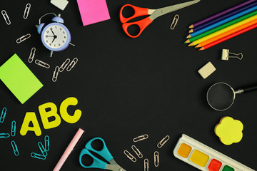 On a black background, school and office supplies are chaotically arranged. In the center there is an empty space for text or an inscription. Pictures on top, mock up.