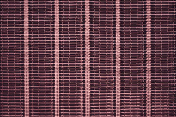 Detailed texture of engine water cooling radiator with vertical lines. Background image of pink automobile part with copy space close up.