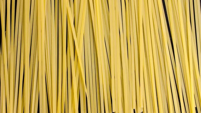Stop motion top view of raw spaghetti on a black table. Close up of pasta background time lapse