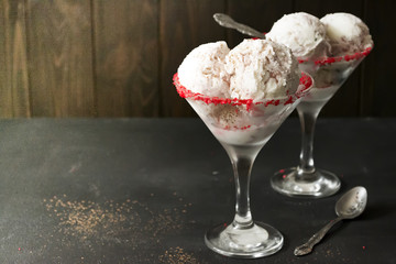 Vanilla ice cream balls in a glass with a spoon on a dark concrete background