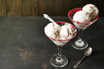 Appetizing creamy white ice cream in a glass with a spoon on a dark concrete background. Copy space