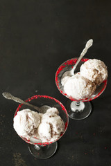 Two glasses with tasty ice cream balls and spoons on a dark concrete background