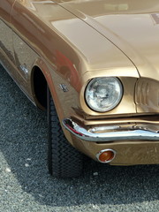 Goldene amerikanische Sportwagen Ikone im Sonnenschein auf grauem Schotter im Sommer beim...