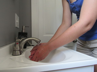 Woman washing her hands with soap in a white sink